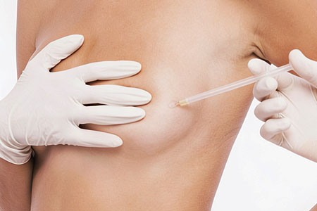 Close view of a woman in a white top resting both hands gently against her chest